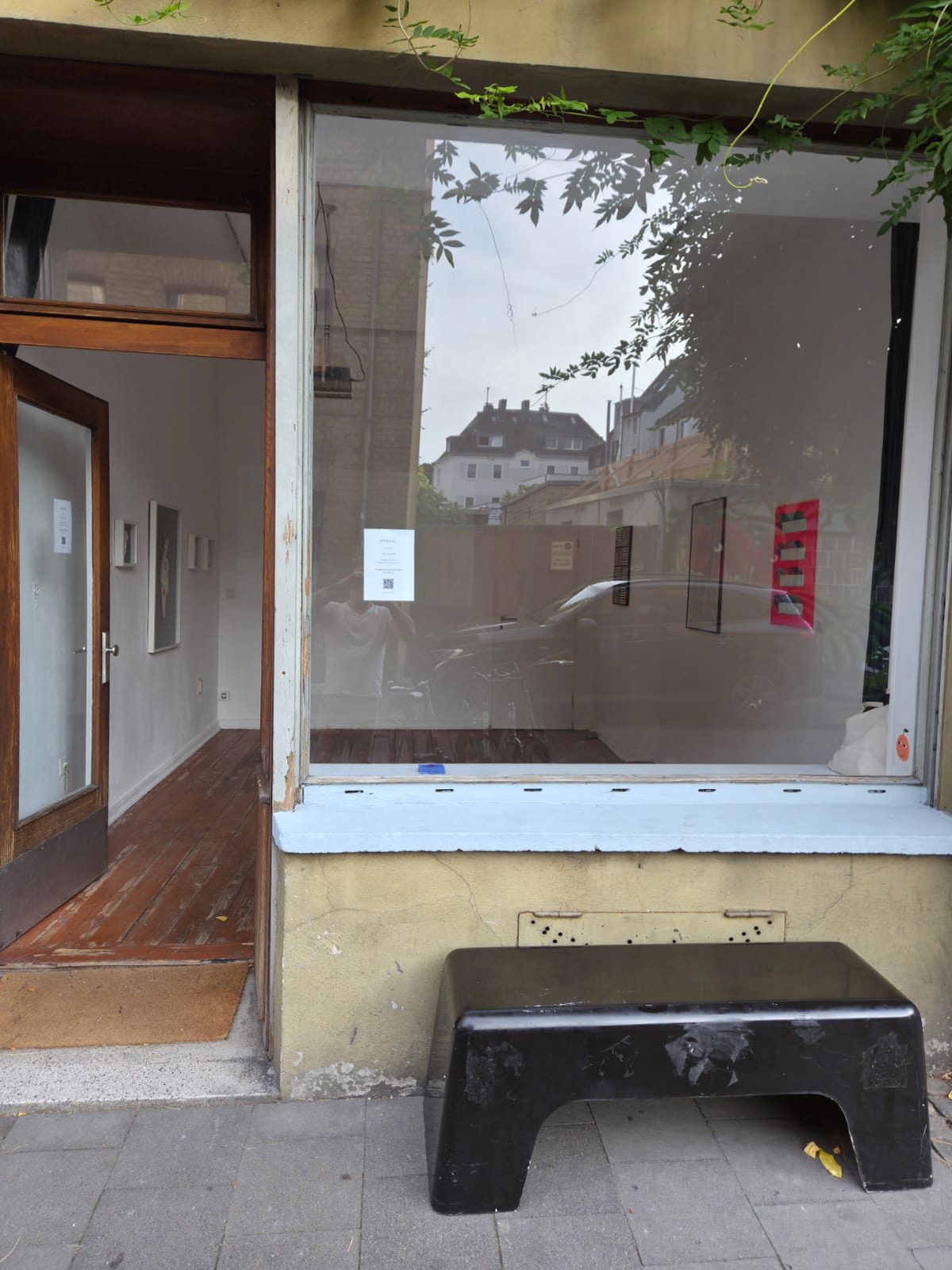 Eingang und Schaufenster der Galerie Szenefeld an der Senefelderstraße, davor eine schwarze Bank